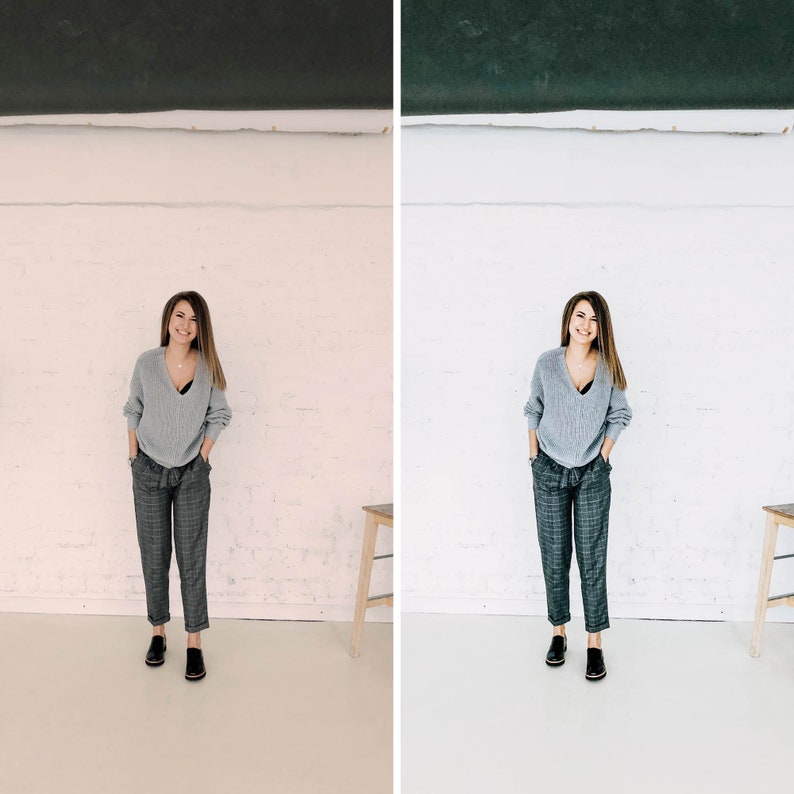 May include: A woman wearing a gray sweater and plaid pants stands in front of a white wall. She is smiling and has her hands in her pockets.