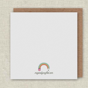 May include: Blank white card with a rainbow and pencil design. The text "magicallycrafted.com" is printed below the design.