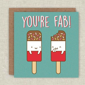 May include: A greeting card with a blue background and the text "YOU'RE FAB!" in white. Two cartoon popsicles with chocolate and sprinkles are on either side of the text. The popsicle on the left is whole, and the popsicle on the right has a bite taken out of it.