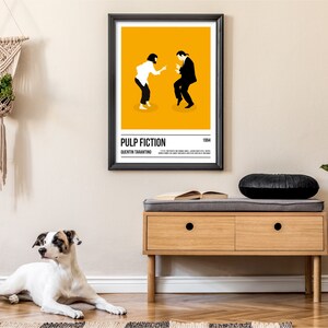 K&ouml;nnte beinhalten: Ein gerahmtes Poster mit einem minimalistischen Design aus dem Film "Pulp Fiction", mit Titel und Name des Regisseurs. Das Poster zeigt zwei Figuren, die vor einem gelben Hintergrund tanzen. Das Poster h&auml;ngt an einer beigen Wand &uuml;ber einer Holzbank.