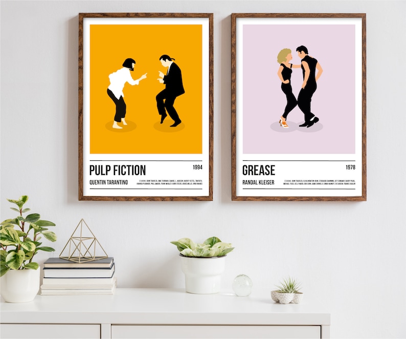 K&ouml;nnte beinhalten: Zwei gerahmte Filmplakate, "Pulp Fiction" und "Grease", werden gezeigt. Das "Pulp Fiction" Poster hat einen gelben Hintergrund mit zwei Figuren. Das "Grease" Poster hat einen lila Hintergrund mit zwei Figuren. Beide Poster haben Text unten.
