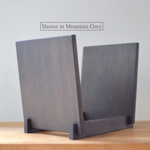 May include: A mountain grey wooden record storage crate with two vertical side panels and a base support. The text "Shown in Mountain Grey" is printed above the object. The structure is composed of flat, rectangular wooden pieces joined together.