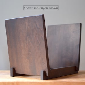 May include: A dark brown wooden record storage crate with a smooth finish and visible wood grain. The structure consists of two upright side panels connected by a base. The text "Shown in Canyon Brown" is printed at the top center.