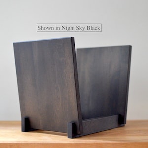 May include: A dark wood record storage crate with a flat base and two upright side panels. The wood features a visible grain pattern in a deep black finish. A rectangular label above the crate contains the text Shown in Night Sky Black.