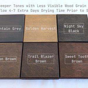 May include: Six square wooden samples arranged in two rows. The top row features Mountain Grey, Golden Harvest, and Night Sky Black. The bottom row shows Canyon Brown, Trail Blazer Brown, and Sweet Tooth Brown. Text reads: Deeper Tones with Less Visible Wood Grain. Please Allow 4-7 Extra Days Drying Time Prior to Shipping.