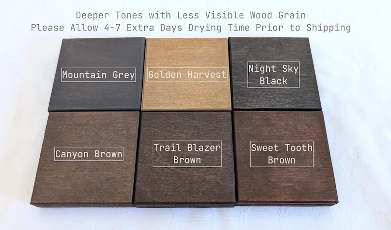May include: Six square wooden samples arranged in two rows. The top row features Mountain Grey, Golden Harvest, and Night Sky Black. The bottom row shows Canyon Brown, Trail Blazer Brown, and Sweet Tooth Brown. Text reads: Deeper Tones with Less Visible Wood Grain. Please Allow 4-7 Extra Days Drying Time Prior to Shipping.