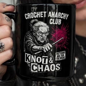 May include: Black ceramic mug featuring the text "CROCHET ANARCHY CLUB" and an illustration of an elderly woman crocheting. The mug also includes the phrases "KNOT & CHAOS" and "PATTERNS ARE FOR THE WEAK."