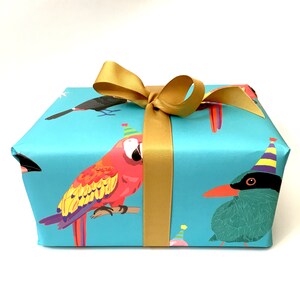 May include: A blue gift box with a gold ribbon and a colourful parrot design. The box is wrapped in paper with a variety of birds wearing party hats.