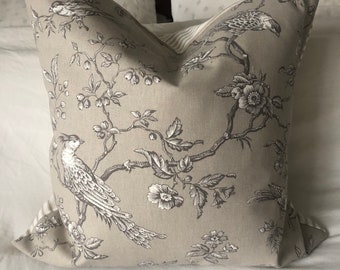 May include: A beige pillow with a black and white floral pattern featuring birds. The pillow is made of a soft, linen-like fabric.