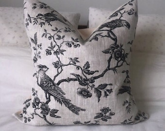 May include: A decorative throw pillow with a black and white floral pattern featuring birds on branches. The pillow is made of a linen fabric.