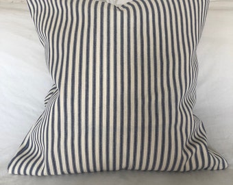 May include: A white pillow with blue stripes. The pillow is made of a soft, woven fabric.