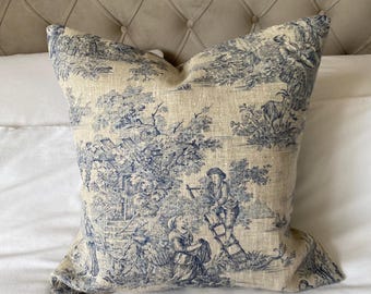 May include: A blue and white toile patterned throw pillow with a linen texture. The pillow features a pastoral scene with figures and trees.