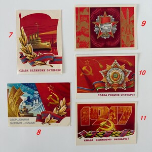 May include: Five rectangular vintage postcards featuring Soviet-themed illustrations in red, gold, and blue. The cards display imagery of ships, stars, hammers, sickles, wheat, and industrial scenes with Cyrillic text including SVERSHENIYAM OKTYABRYA.