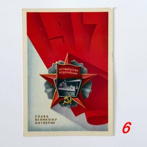May include: A rectangular postcard featuring a red star emblem with a central shield depicting a ship. The shield displays a red flag with the text OКТЯБРЬСКАЯ РЕВОЛЮЦИЯ. Below the star is a gold hammer and sickle. The text SLAVA VELIKOMU OKTYABRYU appears at the bottom.