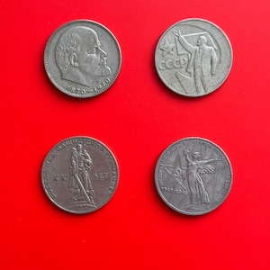 Puede incluir: Cuatro monedas de color plateado con diferentes diseños. La moneda de la parte superior izquierda presenta un retrato de un hombre con el texto "1870-1970". La moneda de la parte superior derecha presenta a un hombre sosteniendo un martillo y una hoz con el texto "CCCP". La moneda de la parte inferior izquierda presenta a un hombre sosteniendo un rifle con el texto "XX LET". La moneda de la parte inferior derecha presenta a una mujer sosteniendo un martillo y una hoz con el texto "1917-1915".