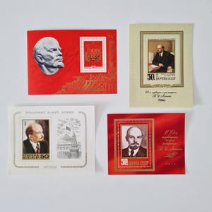 Può includere: Una collezione di francobolli e cartoline commemorative sovietiche vintage con ritratti di Vladimir Lenin. I francobolli e le cartoline sono in vari colori, tra cui rosso, bianco e oro, e presentano testo cirillico.