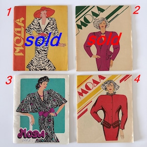 May include: Four vintage fashion magazines titled MODA, featuring illustrated covers of individuals in 1980s style clothing. The covers display various outfits including a zebra print dress, a purple blazer, a floral wrap dress, and a red jacket.