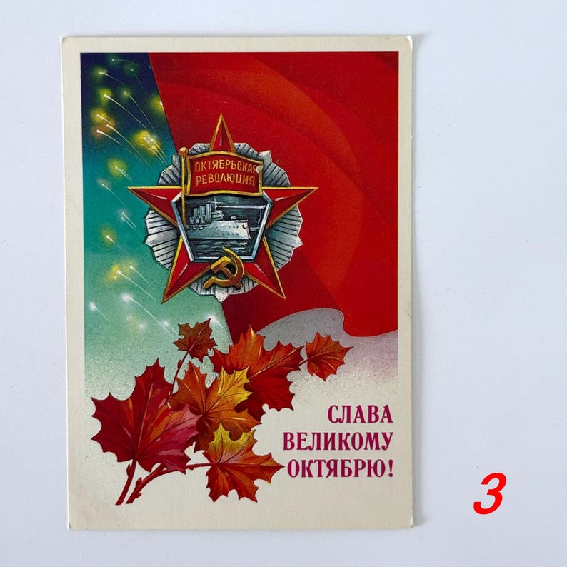 May include: A vintage postcard featuring a red flag background, a central red star emblem with a ship and the text "ОКТЯБРЬСКАЯ РЕВОЛЮЦИЯ", a gold hammer and sickle, autumn maple leaves in red and orange, and the Cyrillic text "СЛАВА ВЕЛИКОМУ ОКТЯБРЮ!" in red.