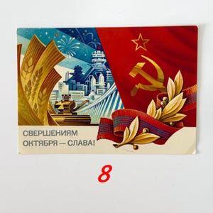 May include: A rectangular postcard featuring a Soviet-themed illustration with a red flag, a gold hammer and sickle, wheat stalks, and an industrial cityscape. The text "СВЕРШЕНИЯМ ОКТЯБРЯ &mdash; СЛАВА!" is printed in the lower left corner in dark gray lettering.