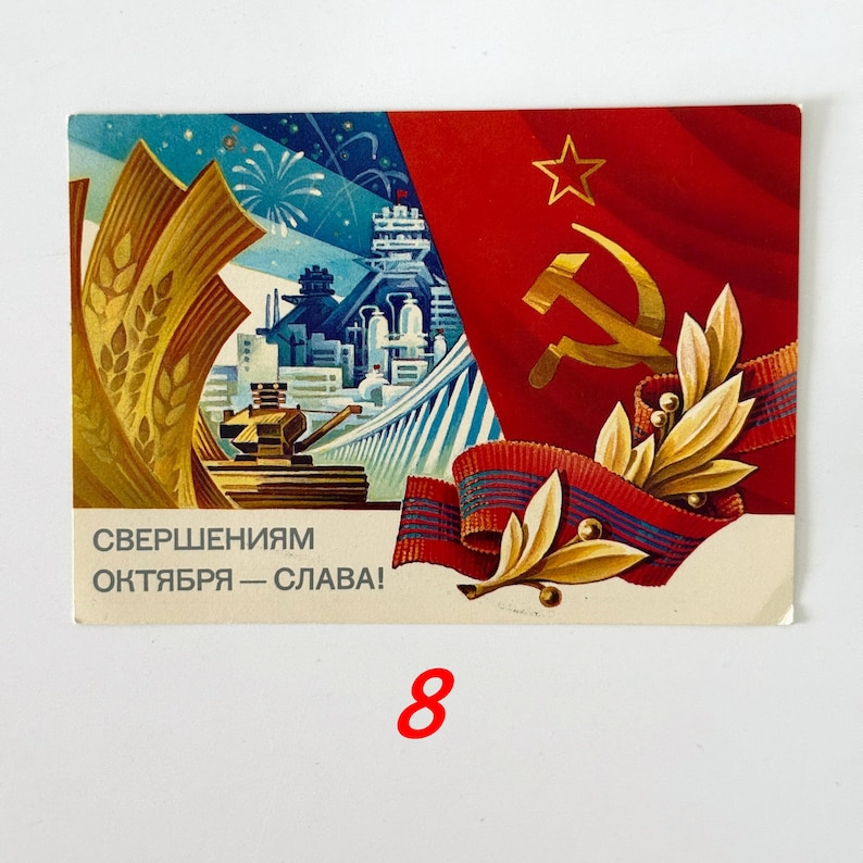 May include: A rectangular postcard featuring a Soviet-themed illustration with a red flag, a gold hammer and sickle, wheat stalks, and an industrial cityscape. The text "СВЕРШЕНИЯМ ОКТЯБРЯ &mdash; СЛАВА!" is printed in the lower left corner in dark gray lettering.