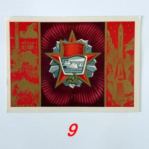 May include: A rectangular postcard featuring a central red star emblem with a ship illustration and the text Oktiabrskaya Revolyutsiya. The left panel shows industrial scenes and figures, while the right panel depicts a Vostok rocket in gold and red.
