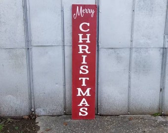 Puede incluir: Un letrero de madera rojo con letras blancas que dice "Merry Christmas".