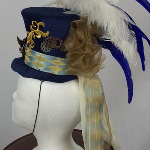 May include: A blue top hat with gold and silver embellishments, a gold and blue ribbon, a white and blue feather plume, and a gold tulle bow.