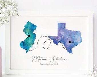 May include: A watercolor print of New Jersey and Texas with a dotted line connecting the two states. The states are painted in shades of blue and green. The text "Melissa + Sebastian" and "September 14th, 2018" is printed below the states.