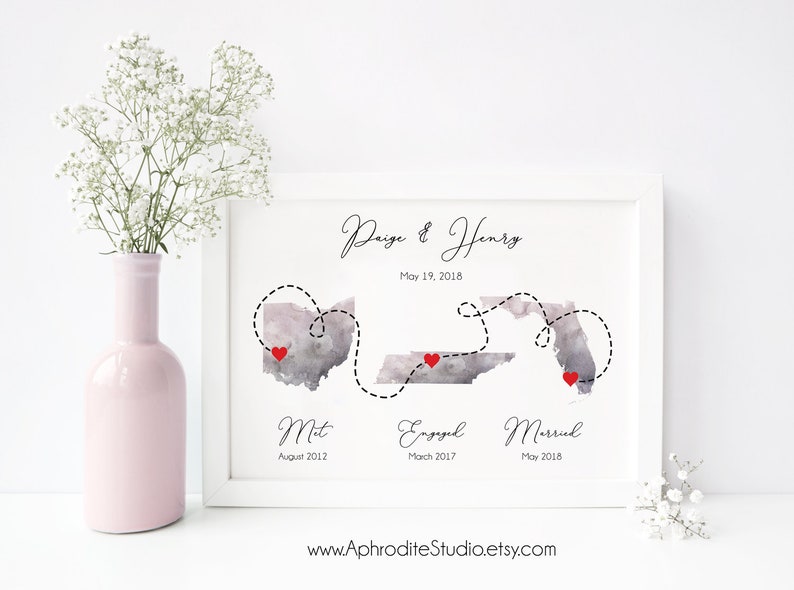 May include: A watercolor print of a map showing the states of Ohio, Tennessee, and Florida. The states are connected by a dotted line with red hearts marking the locations of "Met", "Engaged", and "Married". The text "Paige & Henry" and "May 19, 2018" are at the top of the print. The text "Met August 2012", "Engaged March 2017", and "Married May 2018" are below the map. The website address "www.AphroditeStudio.etsy.com" is at the bottom of the print.