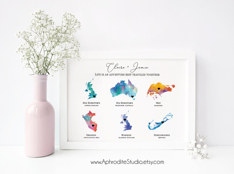 May include: A watercolor print with the names Claire and Jamie and the text "Life is an adventure best traveled together". The print features watercolor maps of different locations with black hearts marking the locations. The locations are labeled with the text "Her Hometown", "His Hometown", "Met", "Engaged", "Married", and "Honeymooned".