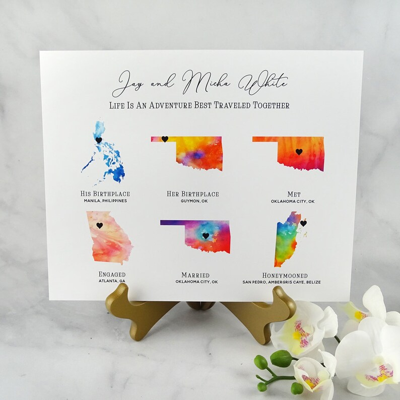 May include: A watercolor map print with the names Jay and Micha White and the text "Life is an adventure best traveled together". The map shows their birthplaces, where they met, got engaged, married, and honeymooned.
