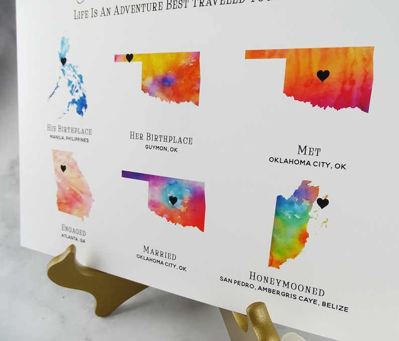 May include: A watercolor map print showing the locations of a couple's life journey. The map shows their birthplaces, where they met, got engaged, married, and honeymooned. The text on the map reads "Life is an adventure best traveled together".