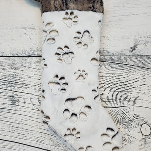 May include: White Christmas stocking with a brown faux fur cuff and paw print design.