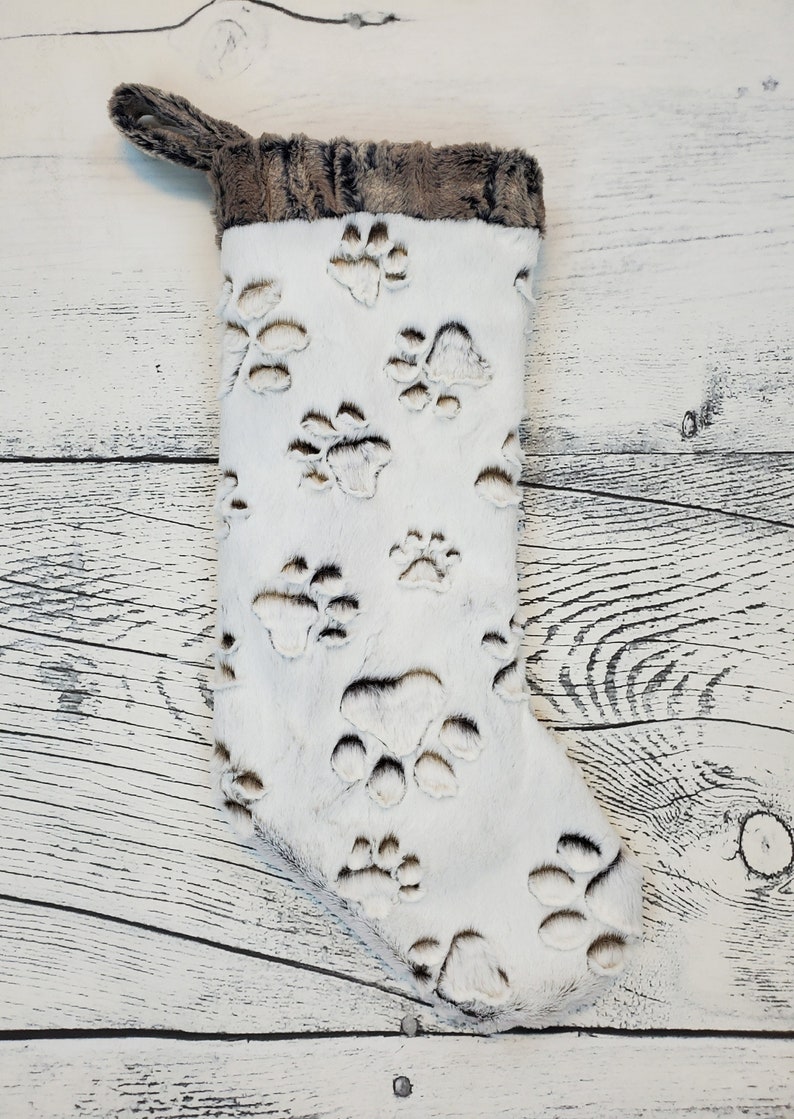 May include: White Christmas stocking with a brown faux fur cuff and paw print design.
