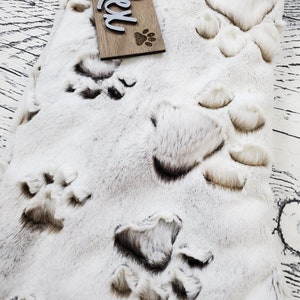 May include: White faux fur stocking with a brown wooden tag that says "Rex" and a paw print. The stocking is decorated with brown paw prints.