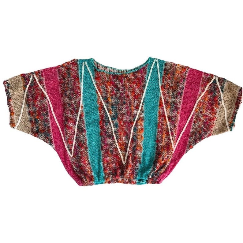 May include: A colorful, patterned knit top with a round neckline and short sleeves. The top features stripes of pink, teal, and tan, with white zigzag accents. The main body of the top is a mix of red, orange, and brown.