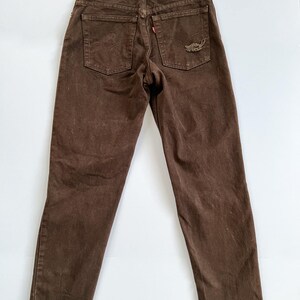 Puede incluir: Vaqueros de mezclilla marr&oacute;n con dobladillos deshilachados. Los vaqueros tienen un peque&ntilde;o parche bordado en el bolsillo trasero que dice "Levi's" y "Original  Quality Clothing".