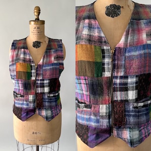 May include: A patchwork vest with a V-neck and a full-length zipper. The vest is made of various plaid fabrics in shades of pink, blue, green, and brown. It is displayed on a vintage mannequin.