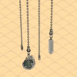 May include: Three silver chains with different pendants. The first chain has a small silver bead at the end. The second chain has a silver dragon pendant with a green gemstone inside. The third chain has a clear crystal pendant.