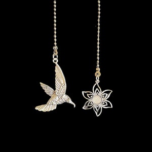 May include: Two silver chain pulls with decorative ends. One end features a hummingbird in flight and the other end features a stylized flower.