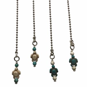 May include: Three silver chains with turquoise and white turtle charms. The chains are made of small silver beads.