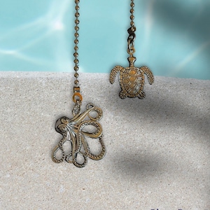 May include: Two decorative ceiling fan pull chains. One chain features a silver octopus design and the other chain features a silver turtle design.