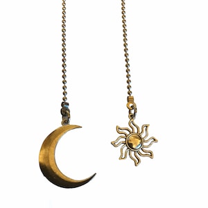 May include: Two silver chains with a crescent moon and a sun pendant. The moon pendant is a simple crescent shape, while the sun pendant has a more detailed design with rays.