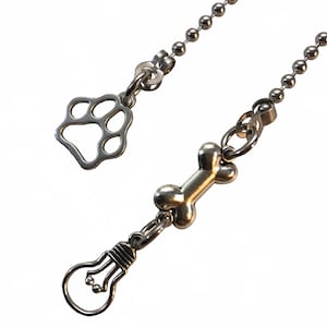 May include: A silver chain with a paw print charm, a bone charm, and a light bulb charm.