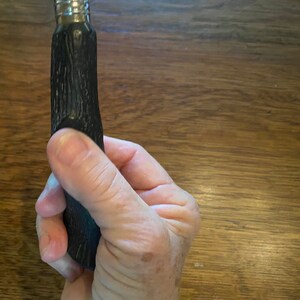May include: A black and silver bottle stopper with a textured, wood-like design.
