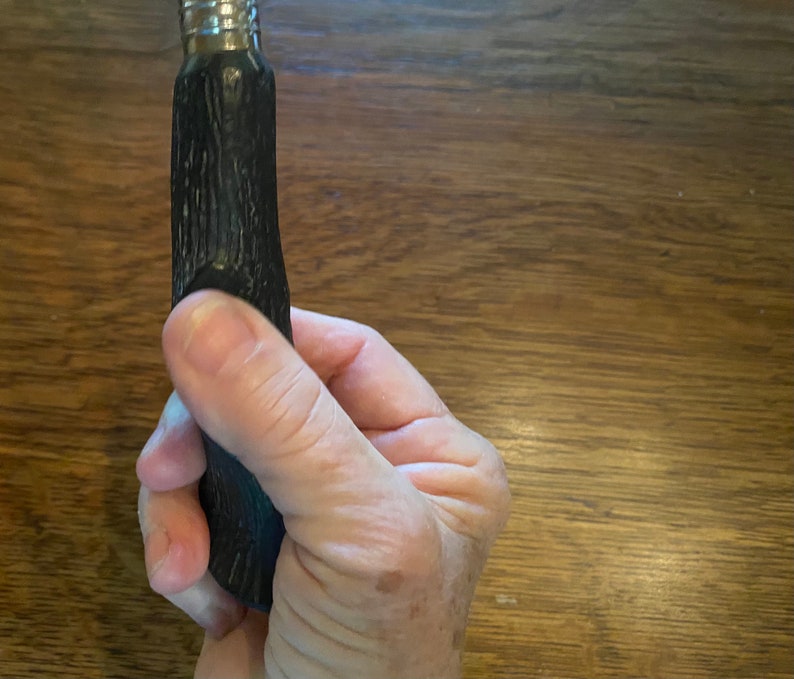 May include: A black and silver bottle stopper with a textured, wood-like design.