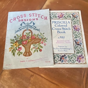 Peut inclure: Deux livres de point de croix vintage. Le premier livre est intitulé "Cross Stitch Designs" et présente un panier de fleurs. Le deuxième livre est intitulé "Priscilla Colored Cross Stitch Book No. 1" et présente une bordure florale.