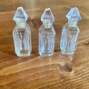 May include: Three clear glass perfume bottles with a diamond-shaped stopper. Each bottle is labelled "YSATIS GIVENCHY PARIS".