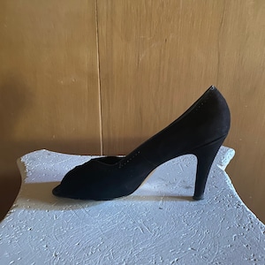 Op de afbeelding: Een zwarte su&egrave;de peep-toe pumps met een stilettohak.