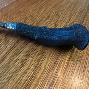 May include: A black metal screwdriver with a wood-grain patterned handle.